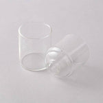 Two clear glass cups on a light gray background