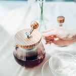 Glass teapot with wooden lid on a table with a blurred background