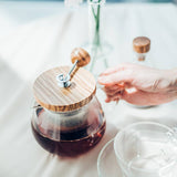 Glass teapot with wooden lid on a table with a blurred background