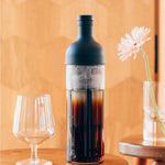 Bottle of cold brew coffee with a glass on a wooden table