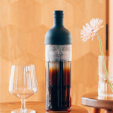 Bottle of cold brew coffee with a glass on a wooden table