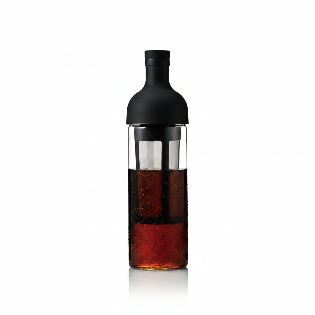 Bottle with a black cap and clear body containing a dark liquid on a white background