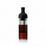 Bottle with a black cap and clear body containing a dark liquid on a white background
