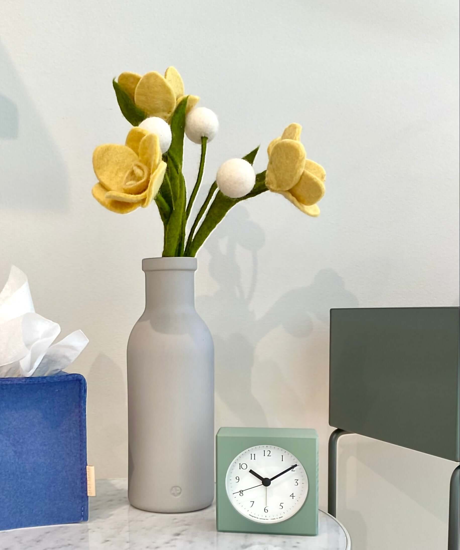 Daffodil Felt Flowers arranged in a tall grey vase on marble end table