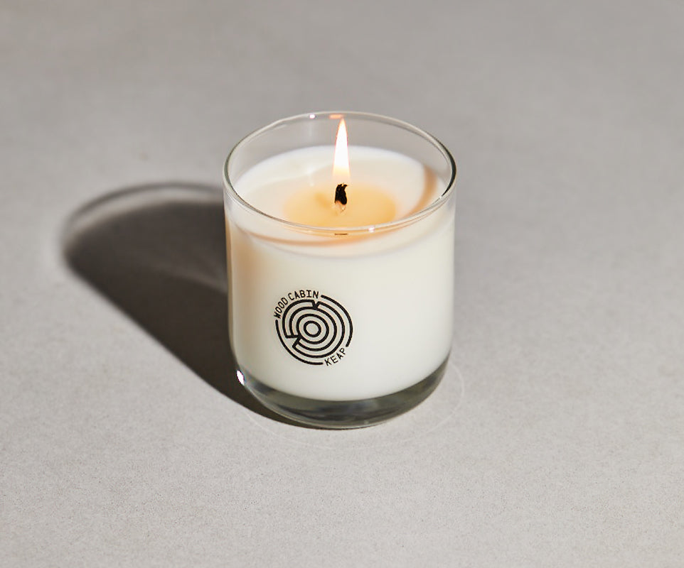Candle in a glass jar with a logo on a gray background