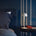 Modern bedroom with a bed, nightstand, and white lamp against a dark blue wall.