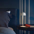 Modern bedroom with a bed, nightstand, and white lamp against a dark blue wall.