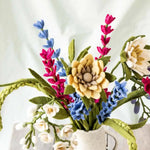 Colorful felt flower bouquet in a white vase on a light background.