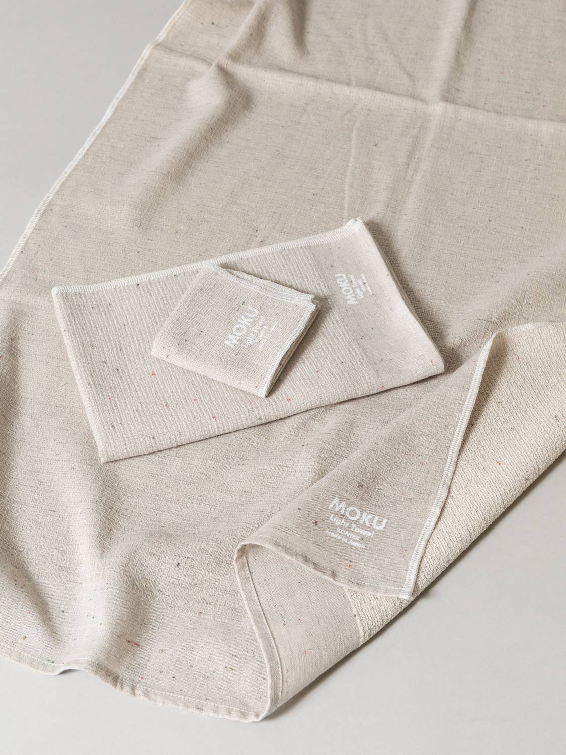 Beige towel set with 'MOKU' branding on a light gray background