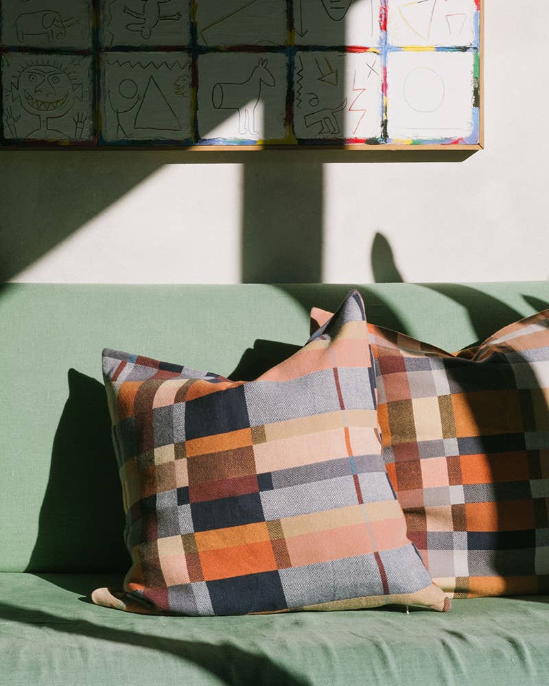 Colorful checkered pillows on a green couch with a wall of colorful blocks in the background.