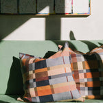 Colorful checkered pillows on a green couch with a wall of colorful blocks in the background.