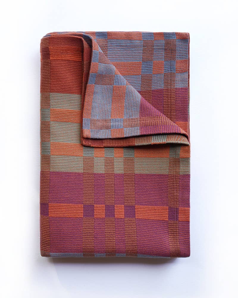 Folded plaid blanket with a geometric pattern on a white background
