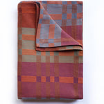 Folded plaid blanket with a geometric pattern on a white background