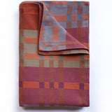 Folded plaid blanket with a geometric pattern on a white background