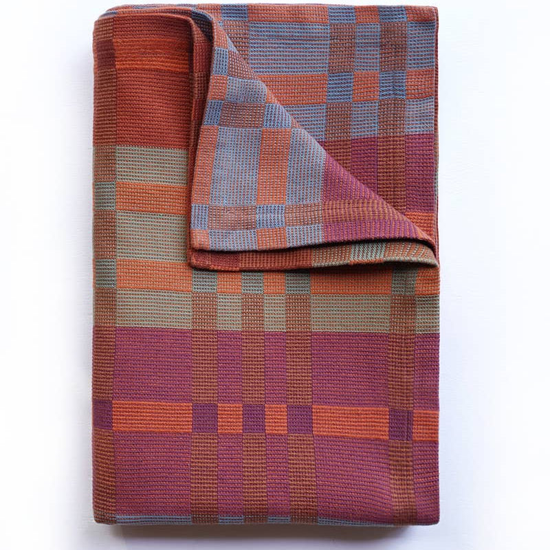 Folded plaid blanket with a geometric pattern on a white background