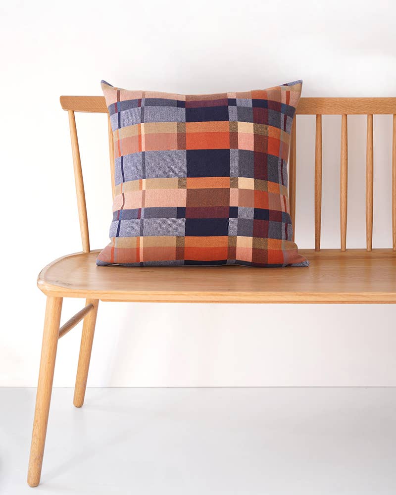 Plaid pillow on a wooden bench against a white background