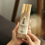 Palo Santo wands in a brown paper packaging held by a person.