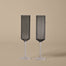 Two ribbed champagne flutes on a beige background