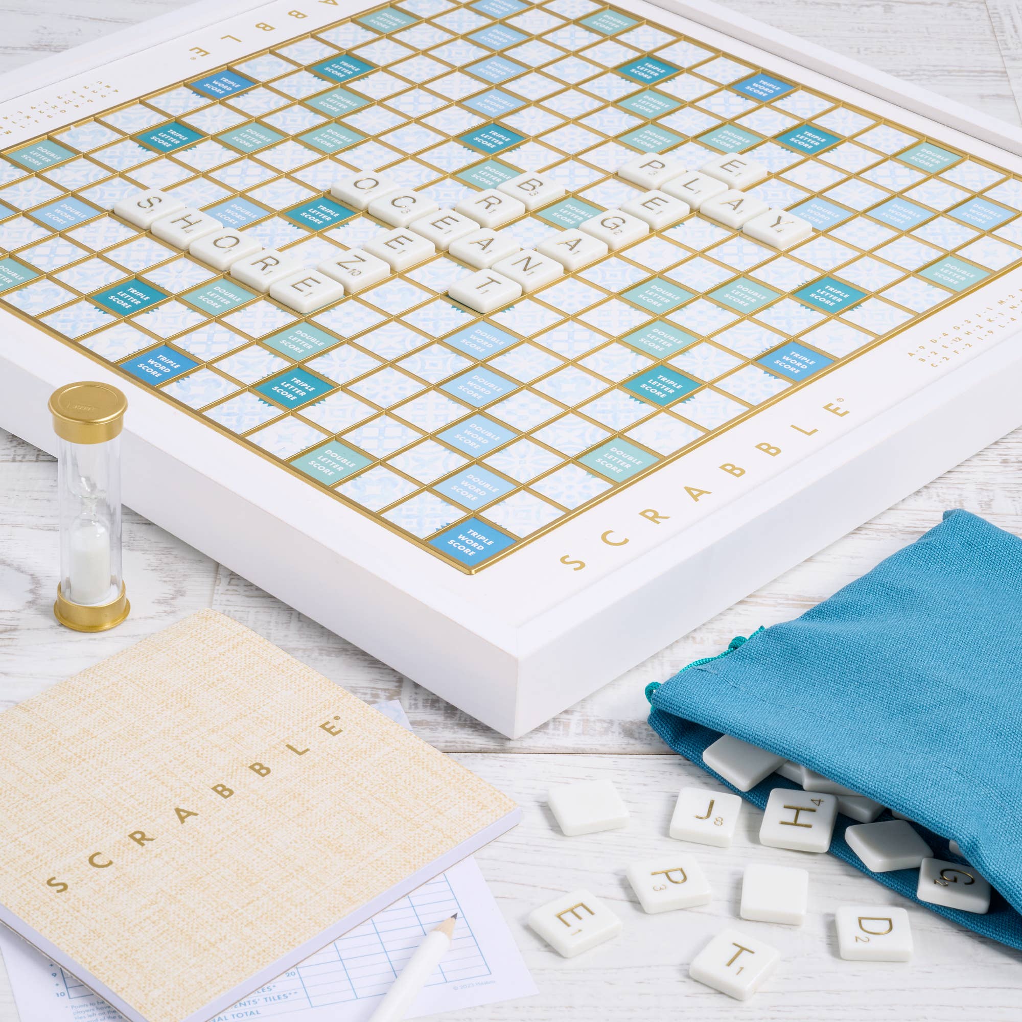 Scrabble game set with board, tiles, and dictionary on a wooden surface