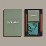 Scrabble game set with green bag and packaging on a beige background