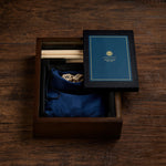 Dark wooden box with blue pouch inside and black folded game board on dark background.