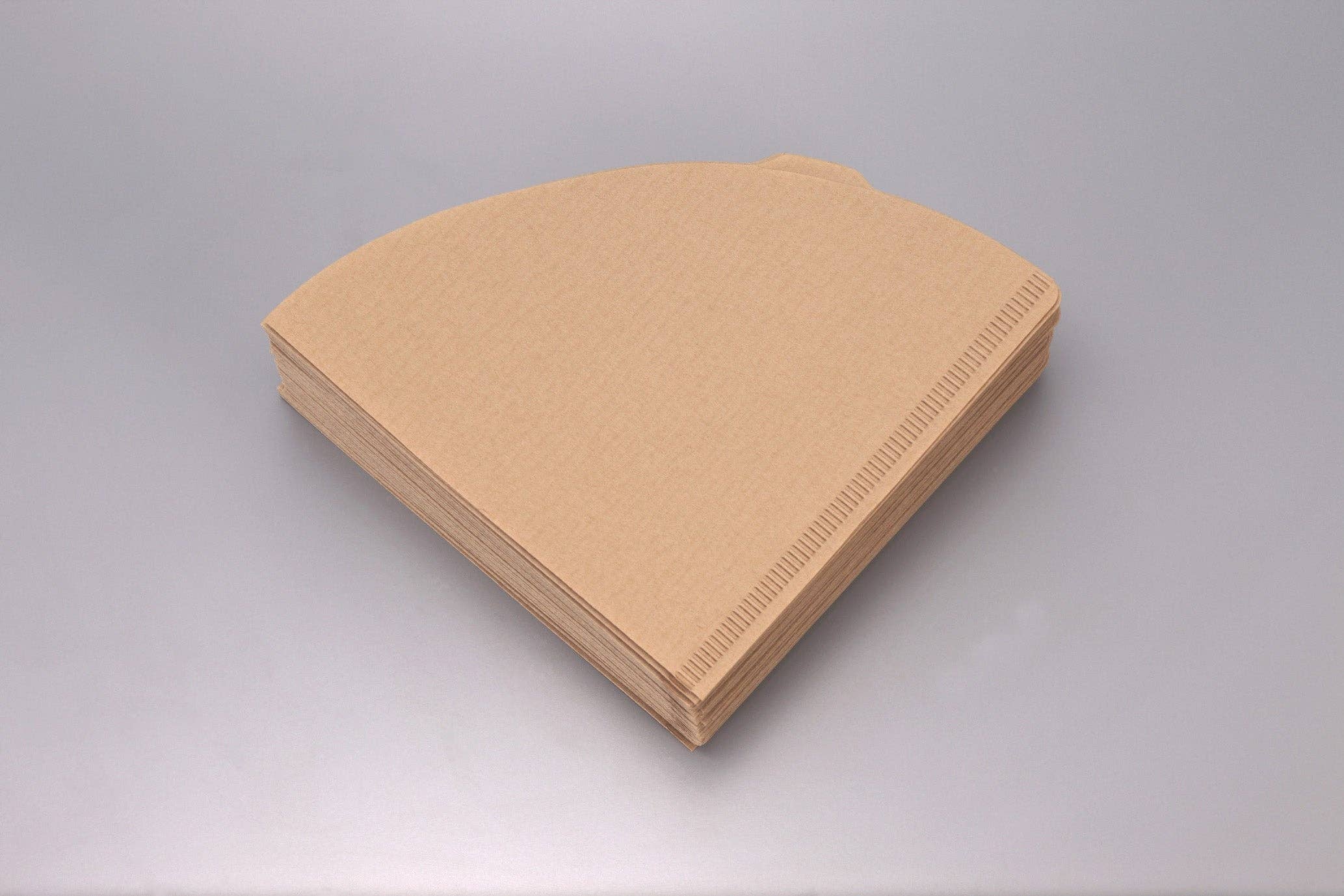 Stack of v shaped brown paper coffee filters on a gray background