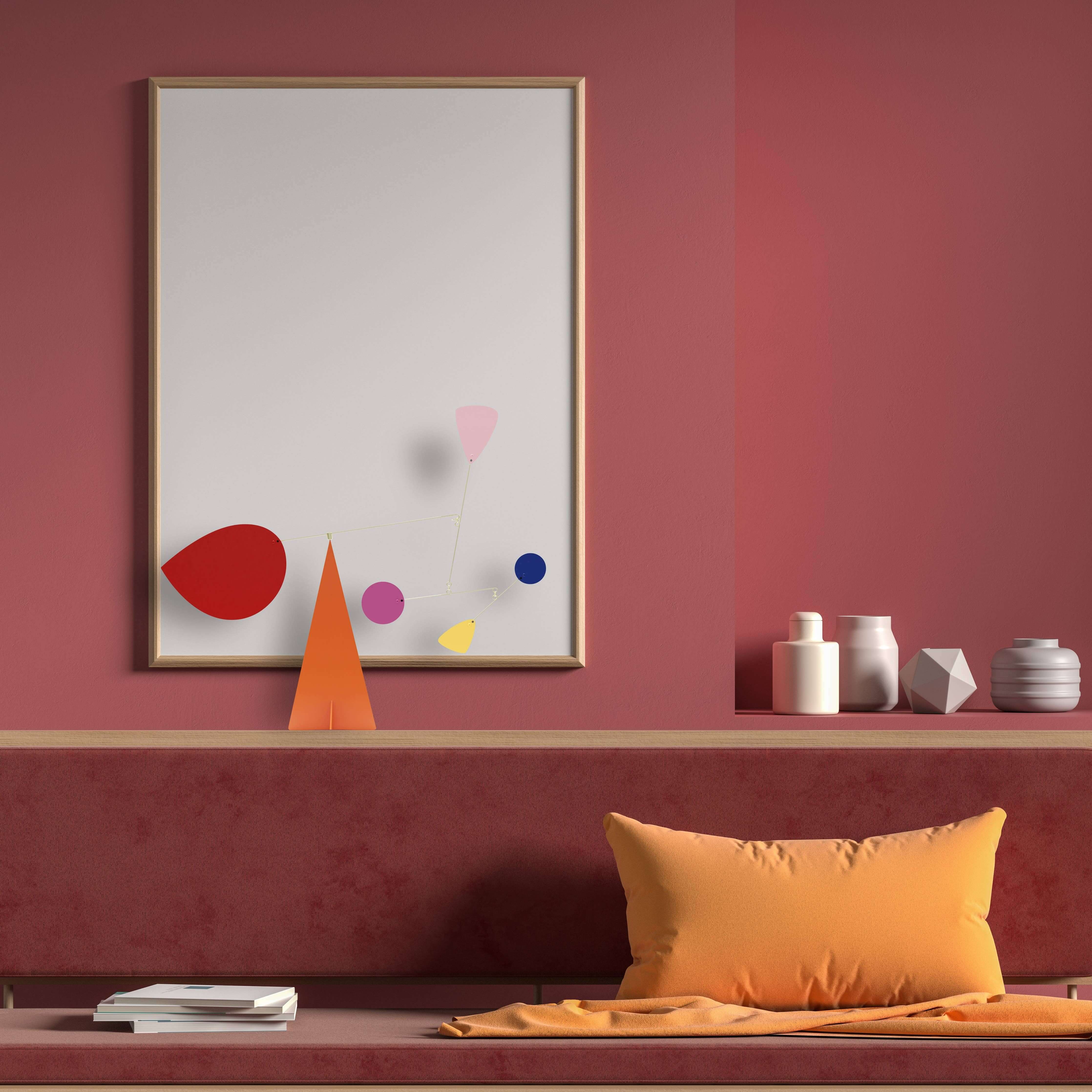 Abstract art piece on a red wall with decorative items below