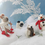 Toy mouse on skis, abominable snowman, polar bear, and snowman in a snowy scene with a blue sky.