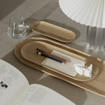 Wooden trays on a table with stationery items and an open book.