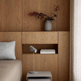 Wooden headboard with a vase, books, and lamp on a neutral background