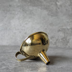 Gold funnel laying on side on a gray surface