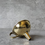 Gold funnel laying on side on a gray surface