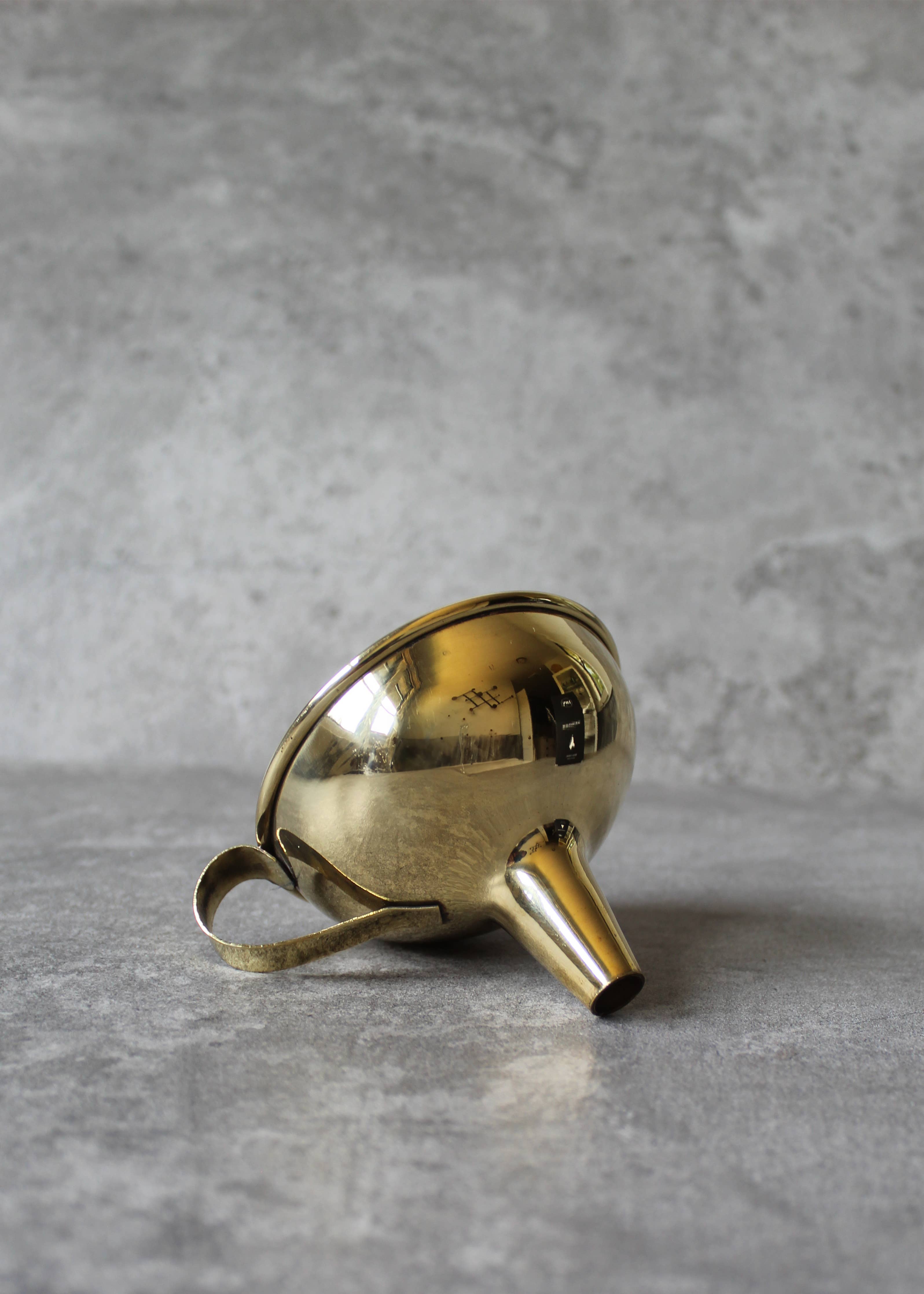Gold funnel laying on side on a gray surface