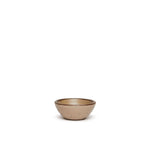 A tiny rounded ceramic bowl in a warm pale brown color featuring iron speckles and an unglazed rim
