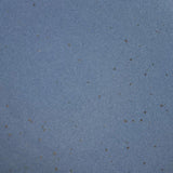 A closeup of a ceramic plate in a cool medium blue color with iron speckles throughout