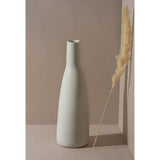 White vase on a neutral background with a dried plant