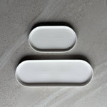 Two white oval trays in two lengths on a textured gray surface