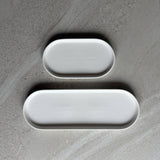 Two white oval trays in two lengths on a textured gray surface