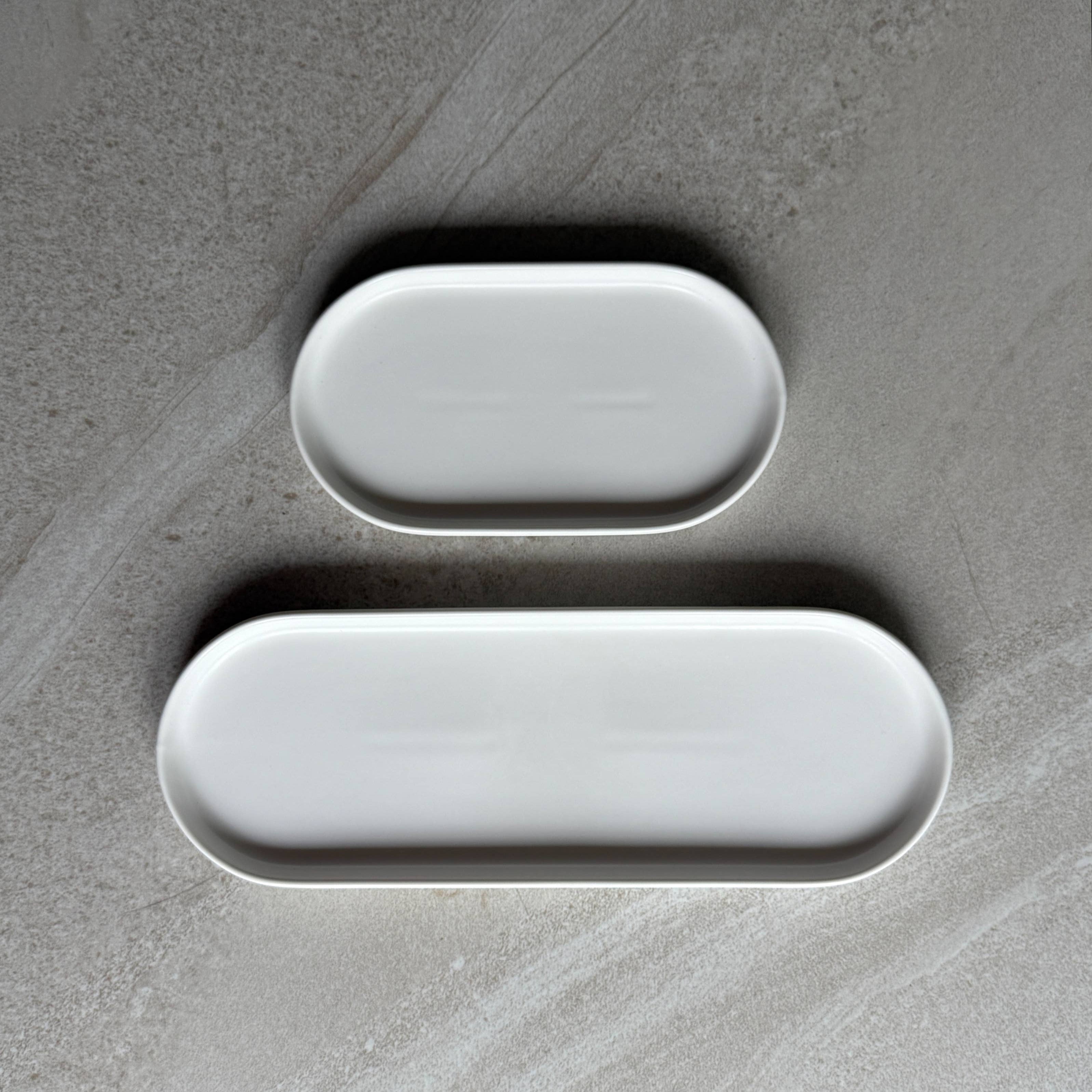 Two white oval trays in two lengths on a textured gray surface