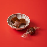 Small white bowl with brown candies on a red background