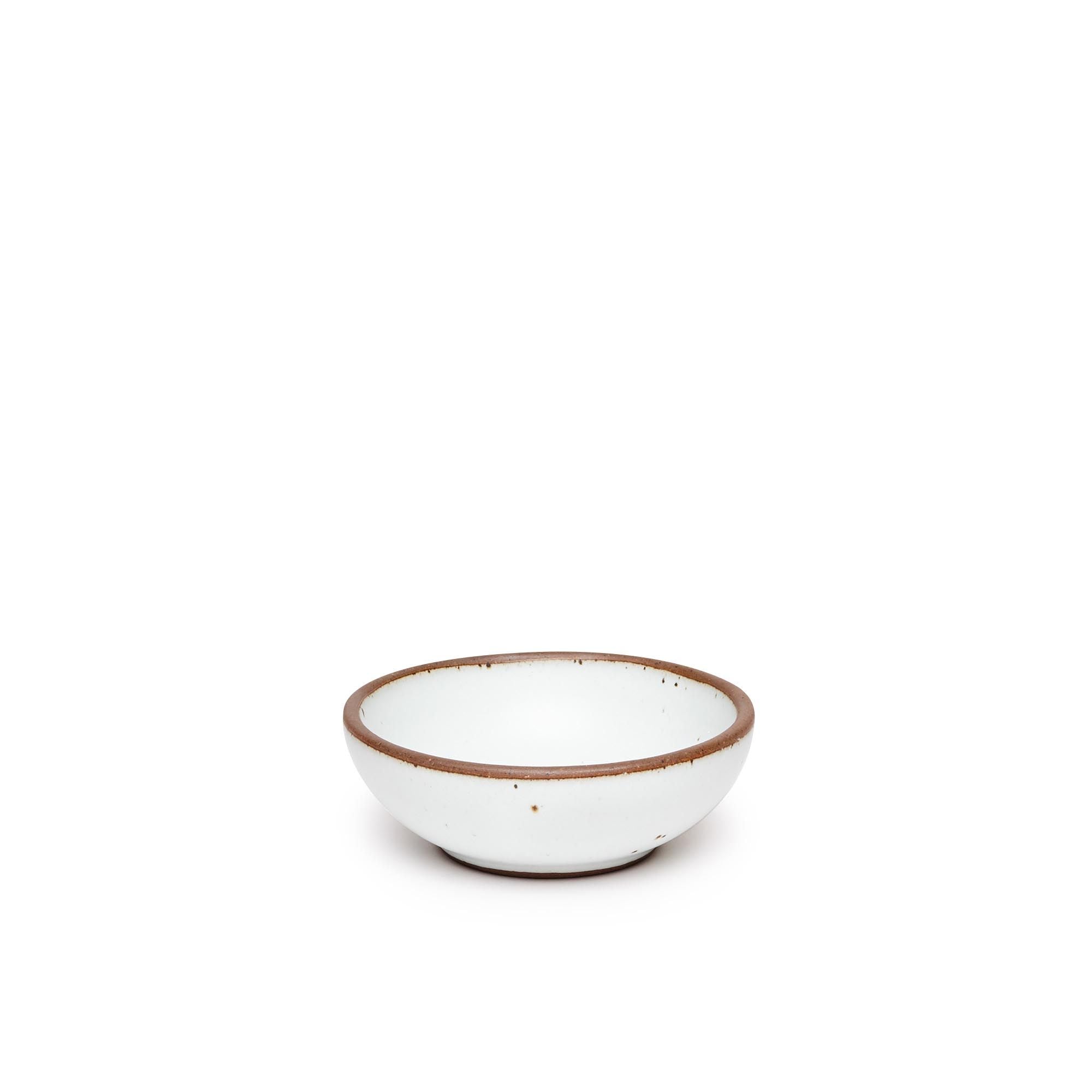 A small shallow ceramic bowl in a cool white color featuring iron speckles and an unglazed rim