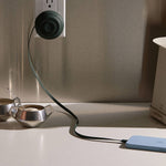 dark green cable plugged into a wall socket on a kitchen counter.