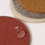 Set of round felt coasters in various colors on a white surface.