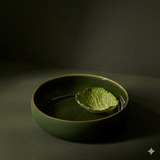 Green ceramic bowl with a leaf of lettuce on a dark background