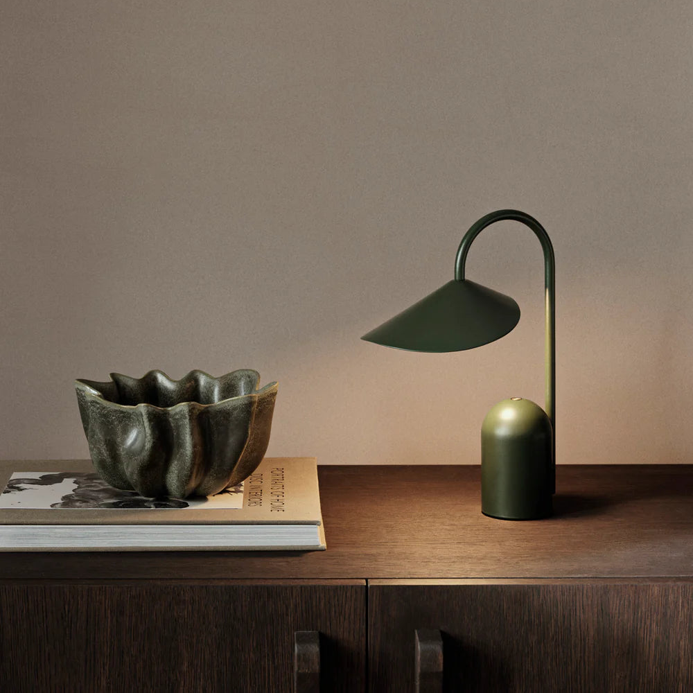 Green lamp and bowl on a wooden surface with a plain background