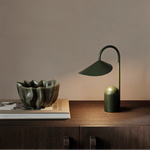 Green lamp and bowl on a wooden surface with a plain background