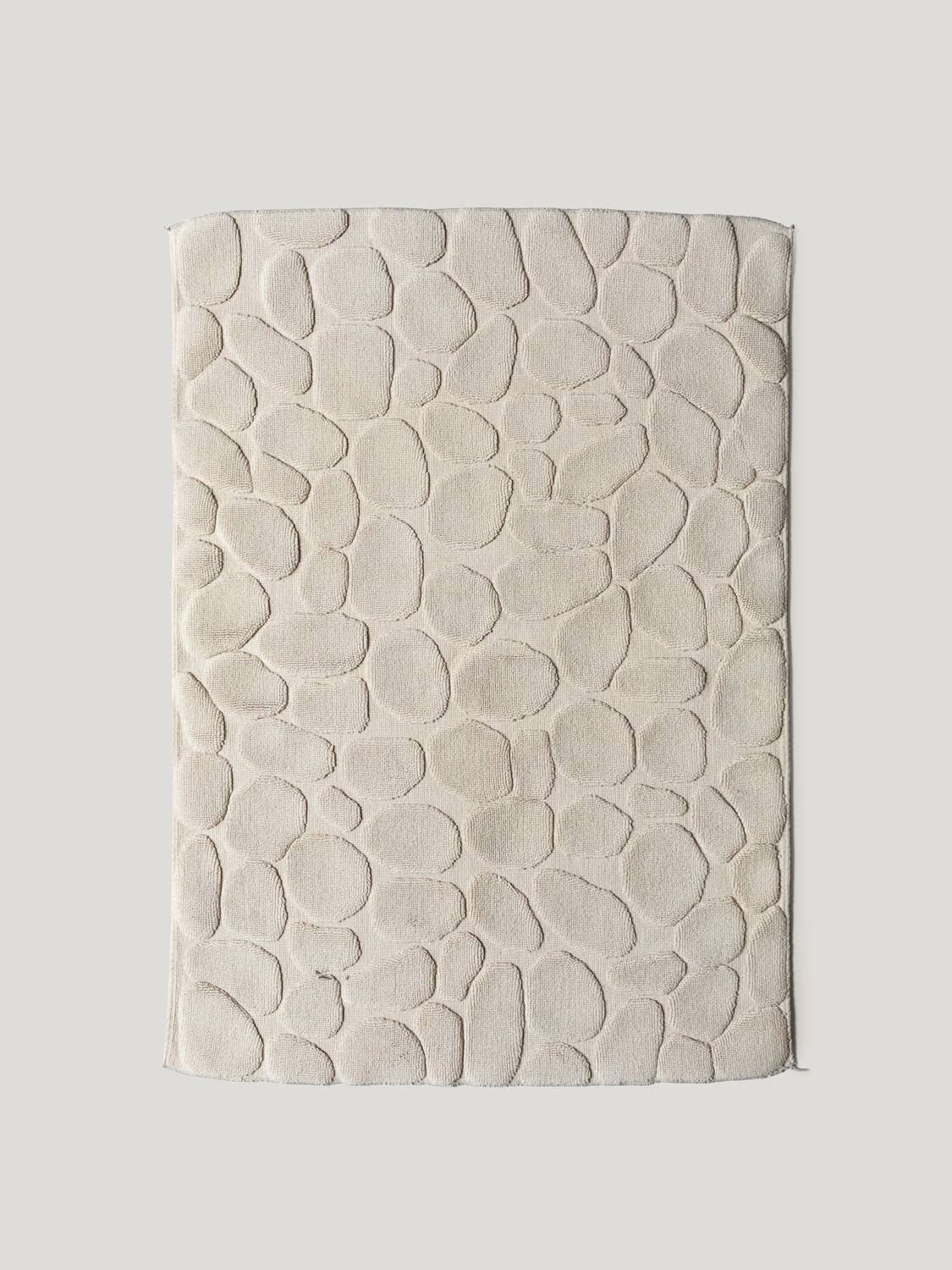 Textured beige bathmat on a light gray background