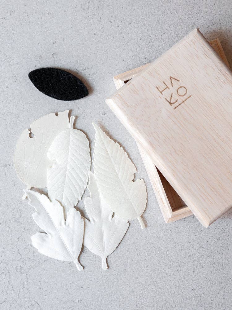 White leaf-shaped objects on a gray surface with a wooden box labeled 'HAKO'.