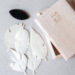 White leaf-shaped objects on a gray surface with a wooden box labeled 'HAKO'.