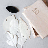 White leaf-shaped objects on a gray surface with a wooden box labeled 'HAKO'.